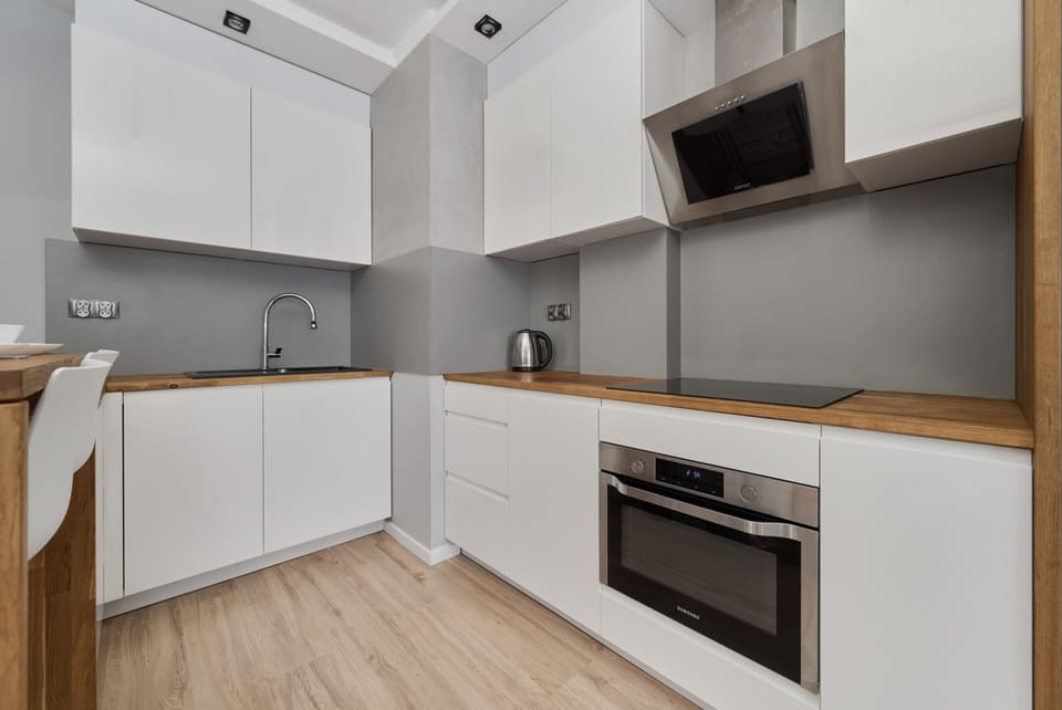 Modern kitchen with white cabinets, a wooden countertop, and built-in appliances.
