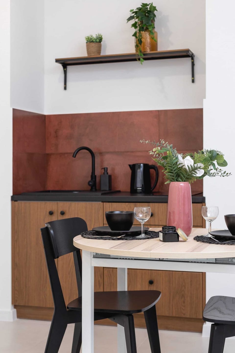 Compact kitchen with built-in appliances, stylish wooden finishes, and red accent walls.
