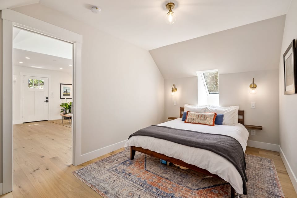 Layered bedding and a skylight-style window make this bedroom feel restful.