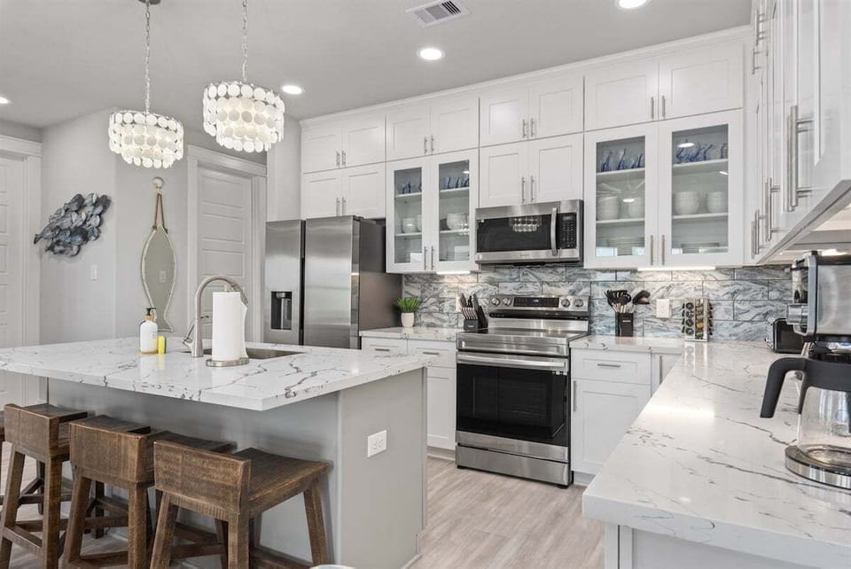Fully equipped gourmet kitchen with stainless steel appliances, large island, bar seating, and quartz countertops.