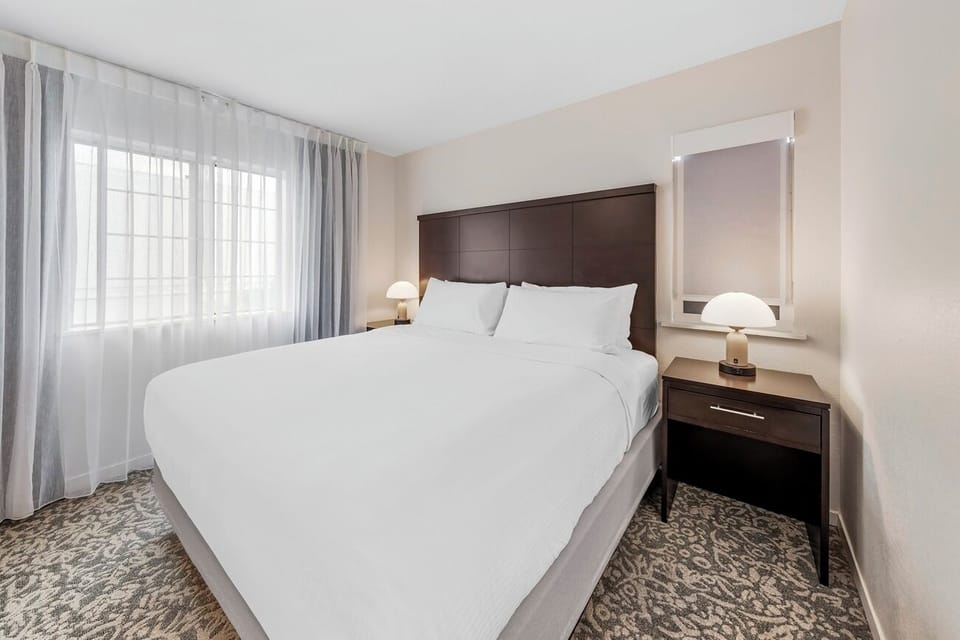 Wake up refreshed in a sunlit bedroom with soft drapes.