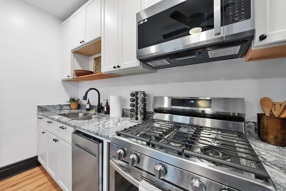 Gas oven and range with cooking utensils and pots and pans provided. 