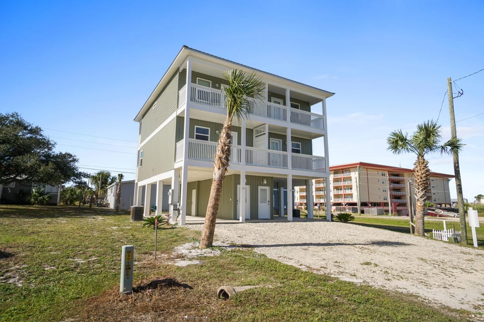 Modern three-story coastal home with spacious balconies and tropical landscaping in a peaceful neighborhood setting.
