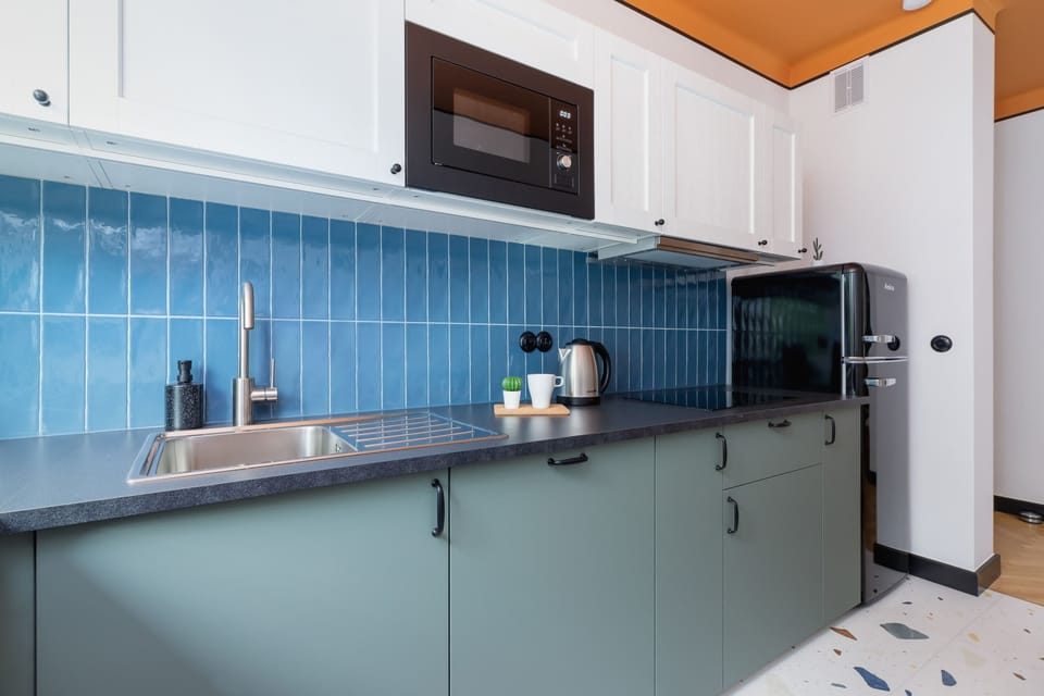 The kitchen area, equipped with blue cabinetry, a modern stove, and a clean, minimalist countertop. The backsplash features a bold, textured design.