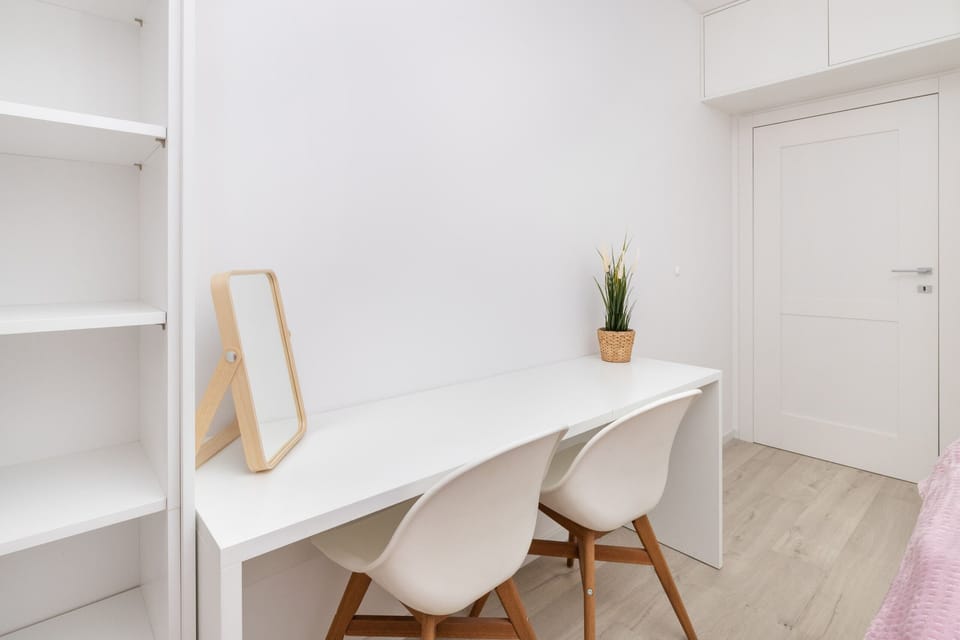 A bedroom with a twin bed setup, complete with blue bedding and modern furnishings. A desk by the window offers a workspace or study area.