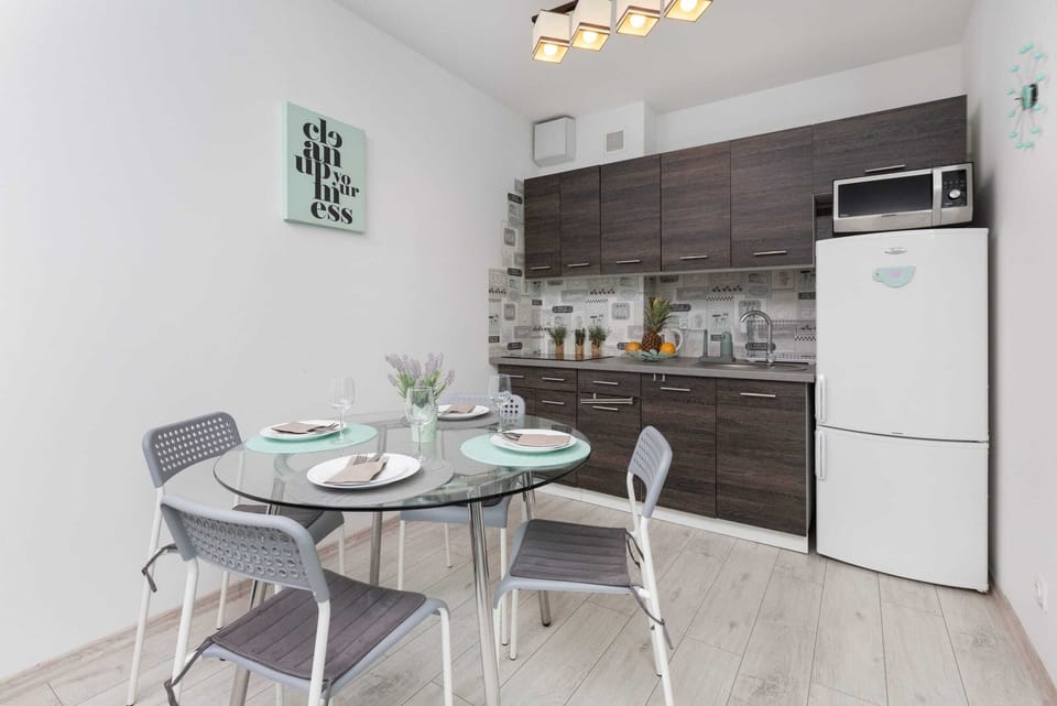 A bright and modern kitchen with a dining table, stylish chairs, and all essential appliances like a refrigerator.