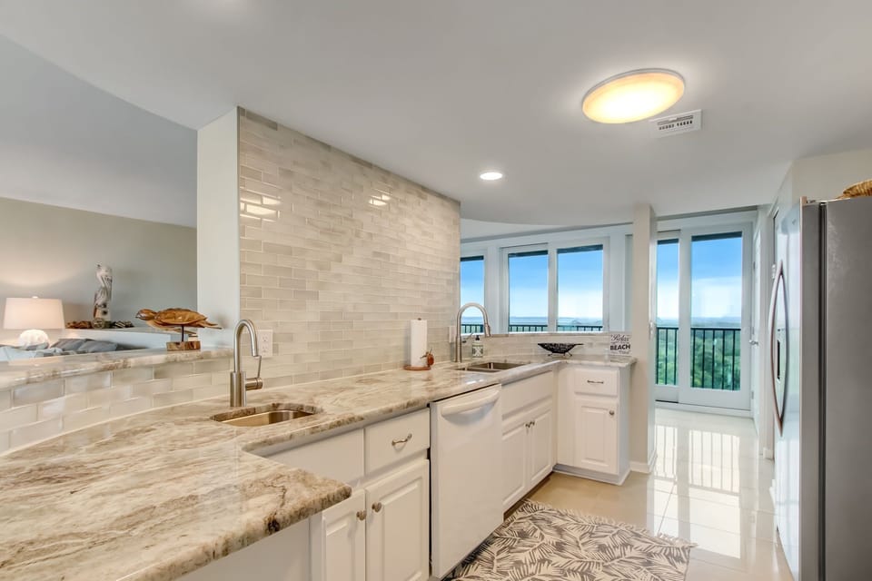 Updated Kitchen with a Marble Countertop, Stainless Steel Appliances, Tiled Backsplash, and Second Sink