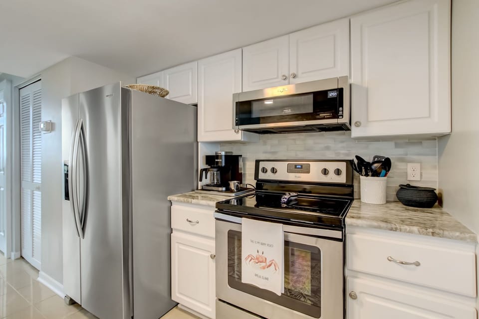 Updated Kitchen with a Marble Countertop, Stainless Steel Appliances, Tiled Backsplash, and Second Sink