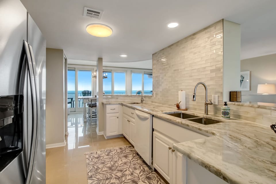 Updated Kitchen with a Marble Countertop, Stainless Steel Appliances, Tiled Backsplash, and Second Sink