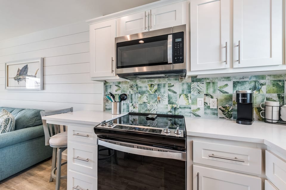 Your bright galley kitchen features modern appliances and tropical backsplash tiles that create a refreshing coastal vibe for your cooking adventures.
