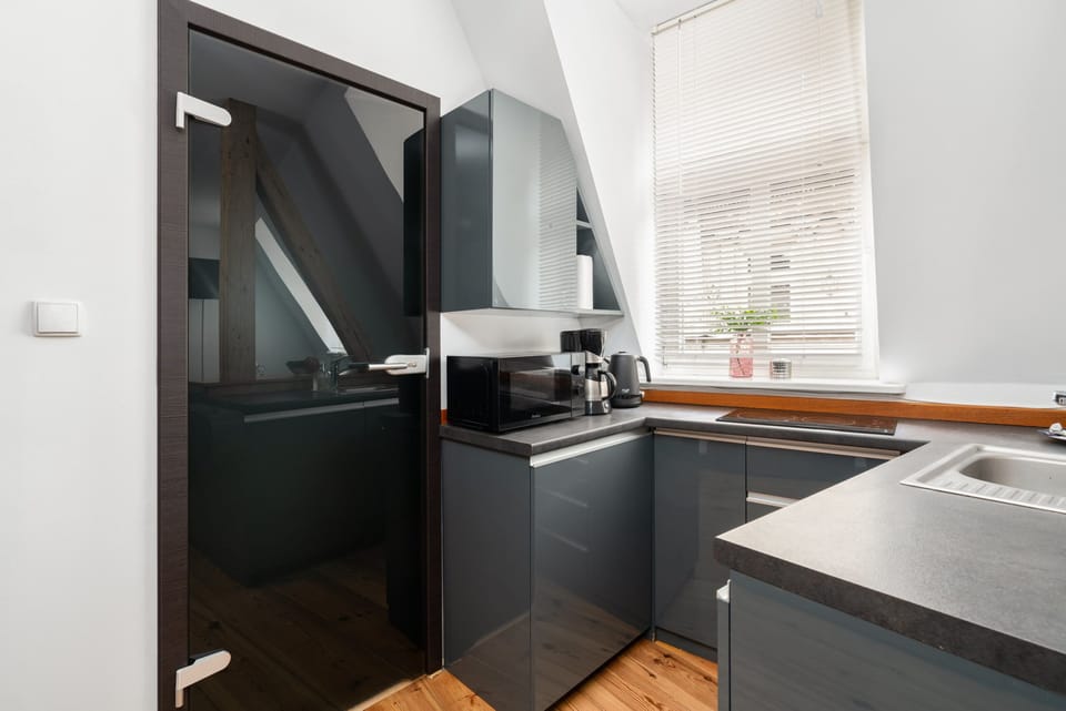 A modern kitchenette with a functional design, featuring ample storage and natural light from a skylight.
