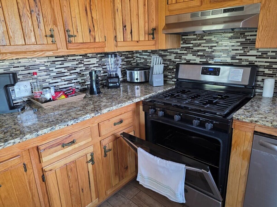 Full kitchen with granite counters, gas range, dishwasher, and window looking
