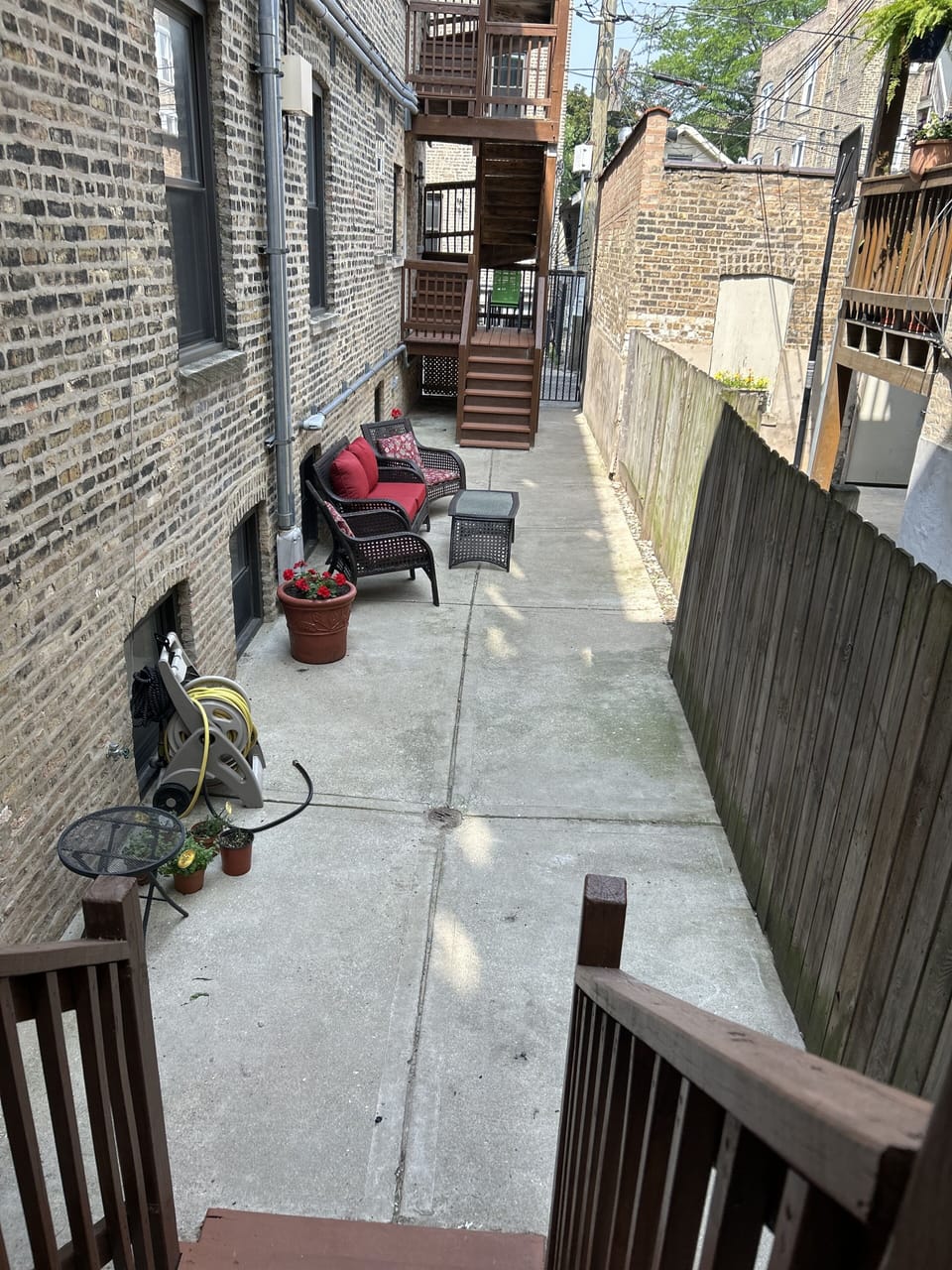 Extended view of enclosed courtyard behind building gated door to garbage bins 