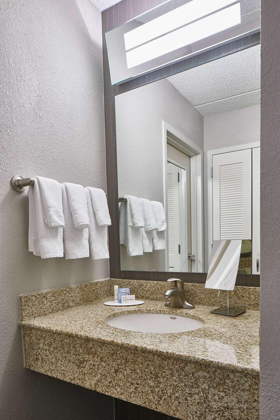 Refresh at the bright granite vanity with fluffy towels.