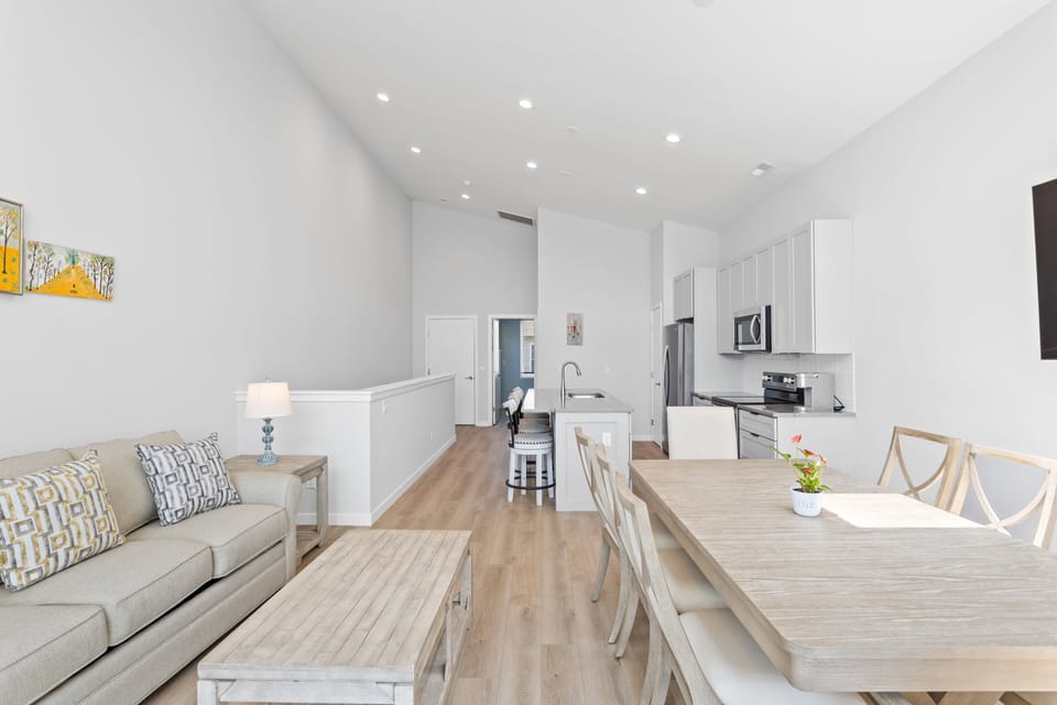 The open living, kitchen, and dining areas with a Smart TV and balcony access
