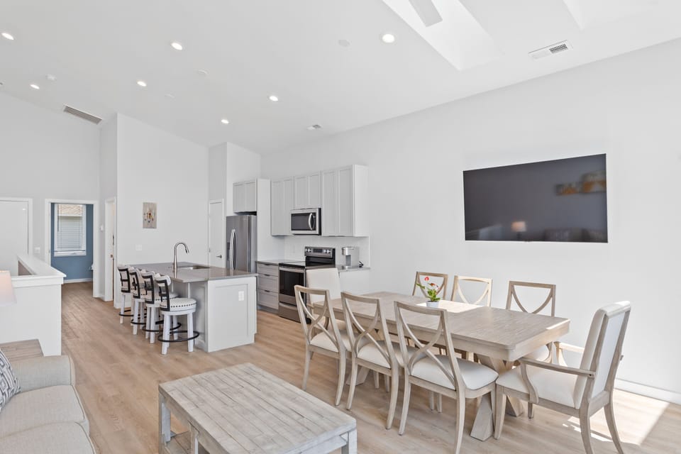 The open living, kitchen, and dining areas with a Smart TV and balcony access
