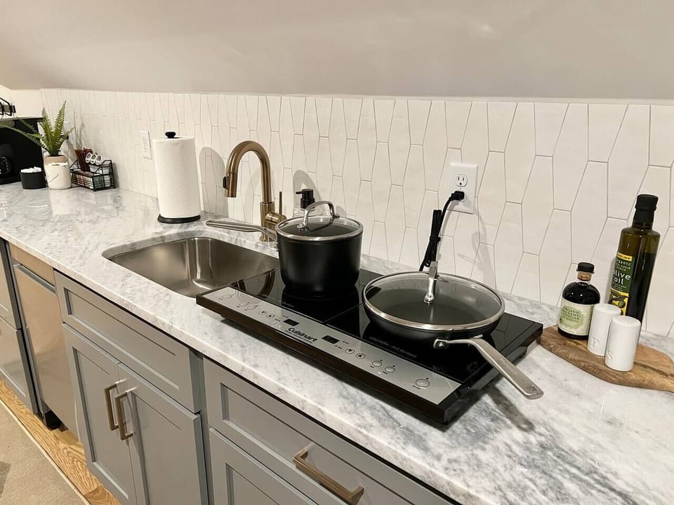 This induction cook top allows cooking with pots and pans like a normal kitchen, but can be stowed away in the cabinet when not in use to free up countertop space.