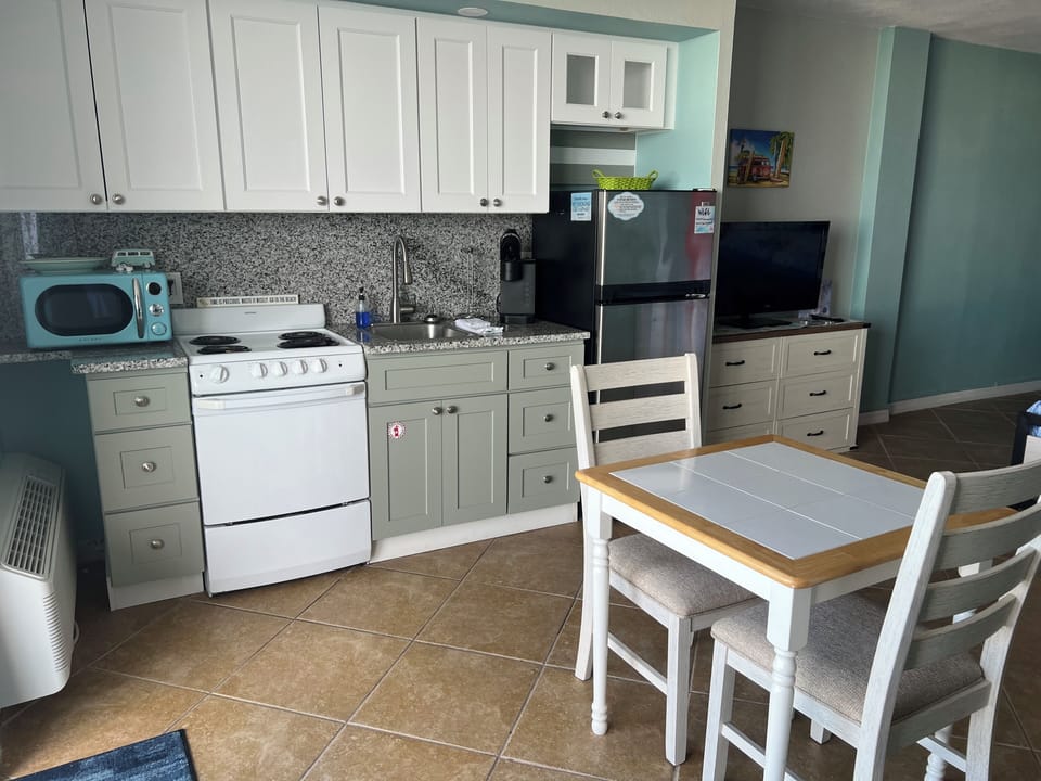 Kitchenette with stove, fridge, microwave, and dining space for two.