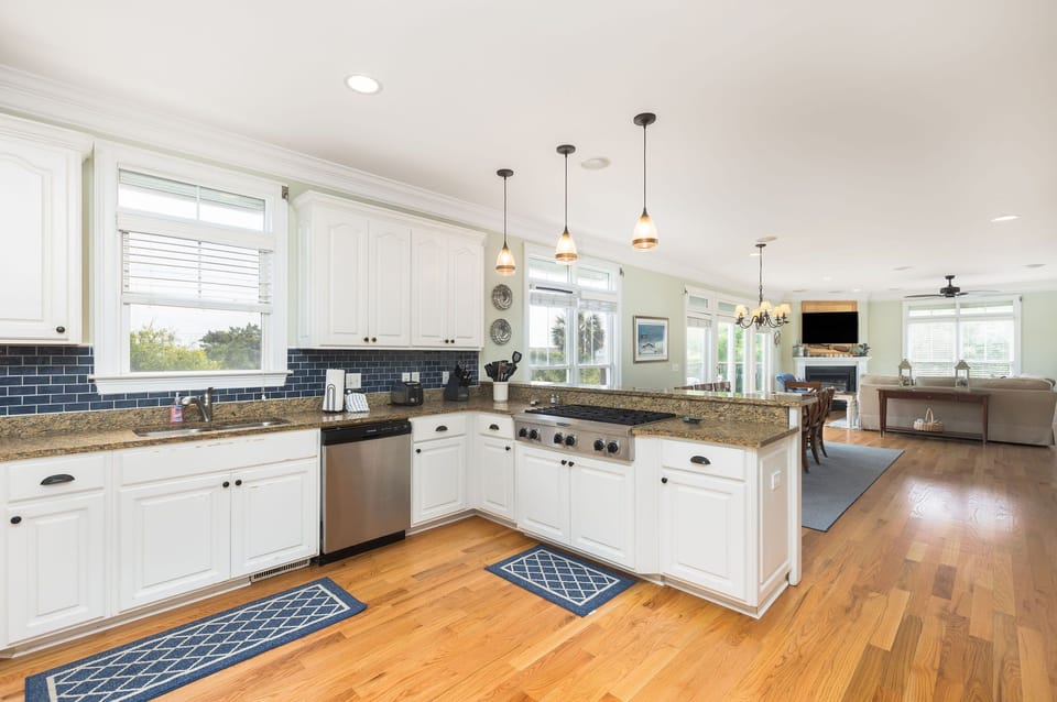 White cabinetry, stainless steel appliances, and modern pendant lighting create an inviting space to cook fresh seafood.