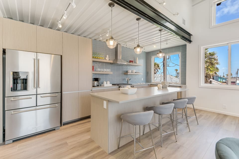 Your sleek modern kitchen awaits with premium appliances, spacious island seating, and bright harbor views through oversized windows.
