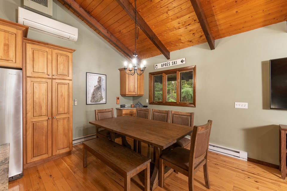 A dining table provides seating for up to 8, while the corner bar is stocked with glasses.