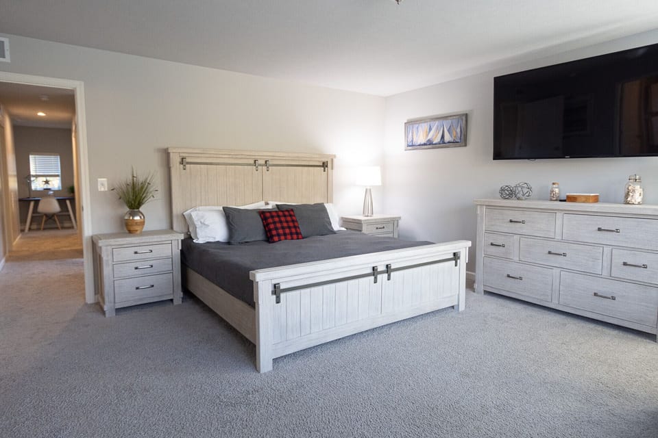 Primary bedroom featuring stylish king bed, matching nightstands and dresser set.