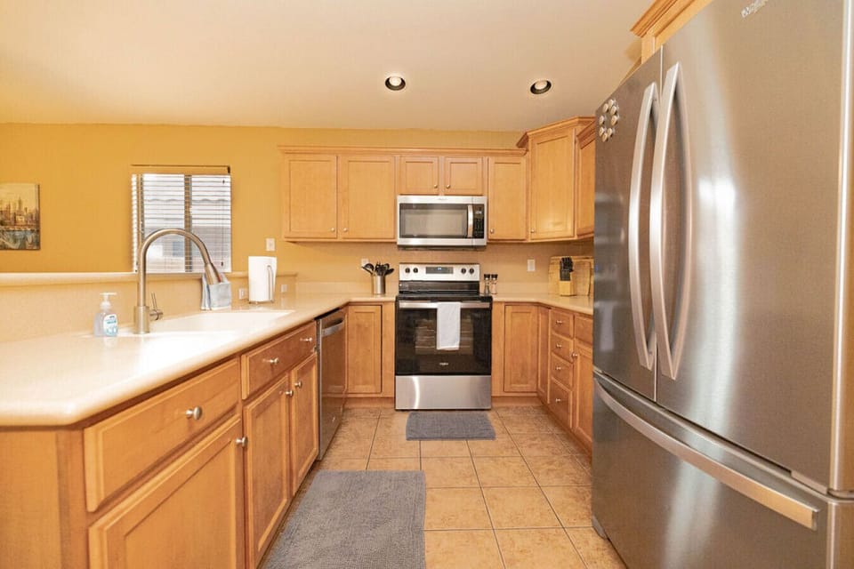 Kitchen with stainless steel appliances, spices, pots, pans, glasses, coffee cups, Tupperware, a Keurig, Crockpot and a pressure cooker!