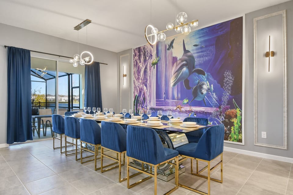 Chic open-concept dining and lounge with ocean mural, velvet chairs, and glam vibes