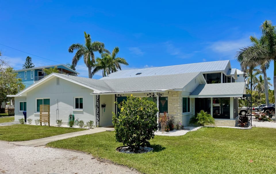 Front of the home with mature palm tree and tropical landscaping
