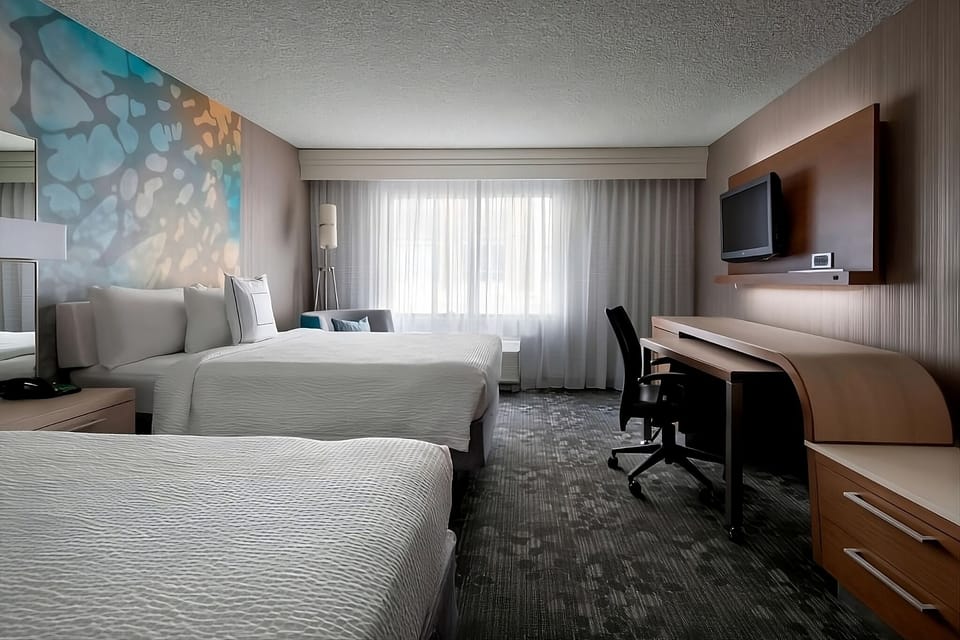 Unwind in a bright double-queen room with dedicated workspace.