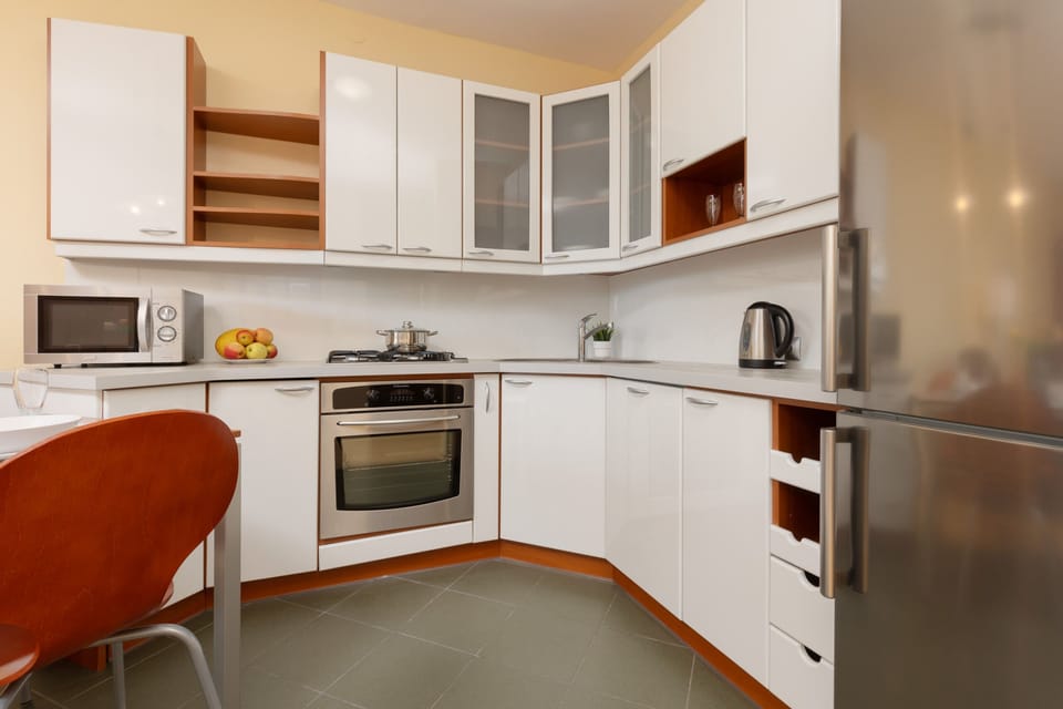 A modern kitchen with white cabinetry, wooden accents, and all essential appliances for convenient cooking.
