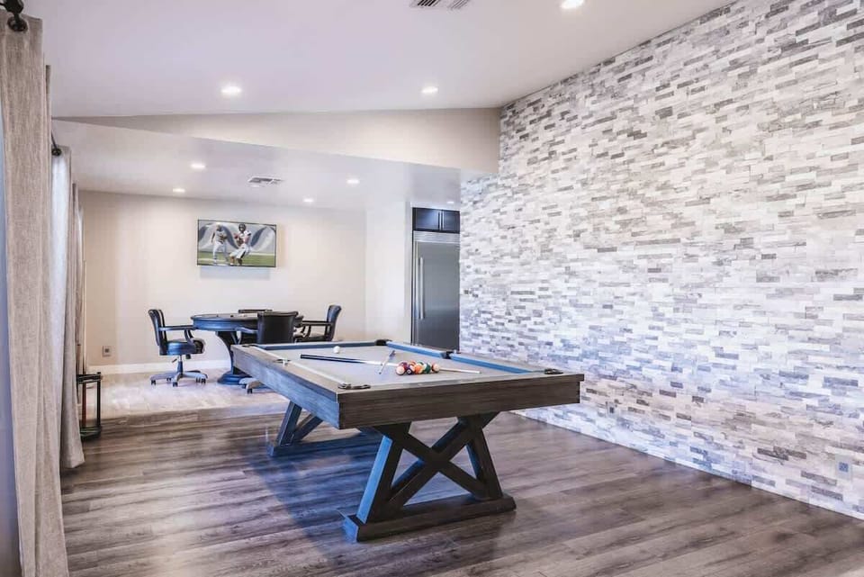 Game room features a pool table and a stacked stone accent wall