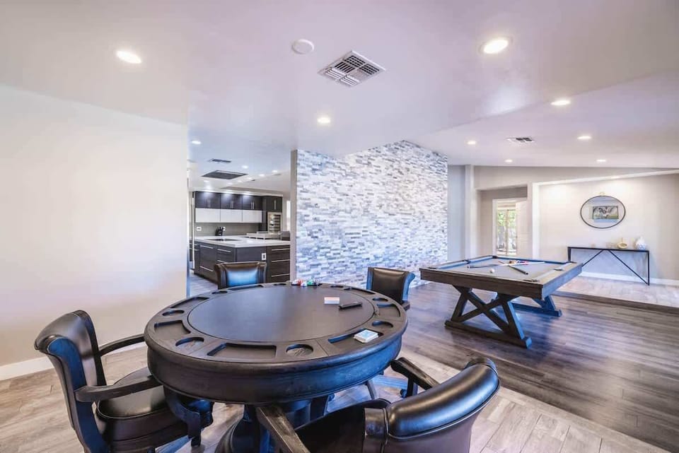 Round poker table with blue leather chairs and stone accent wall backdrop