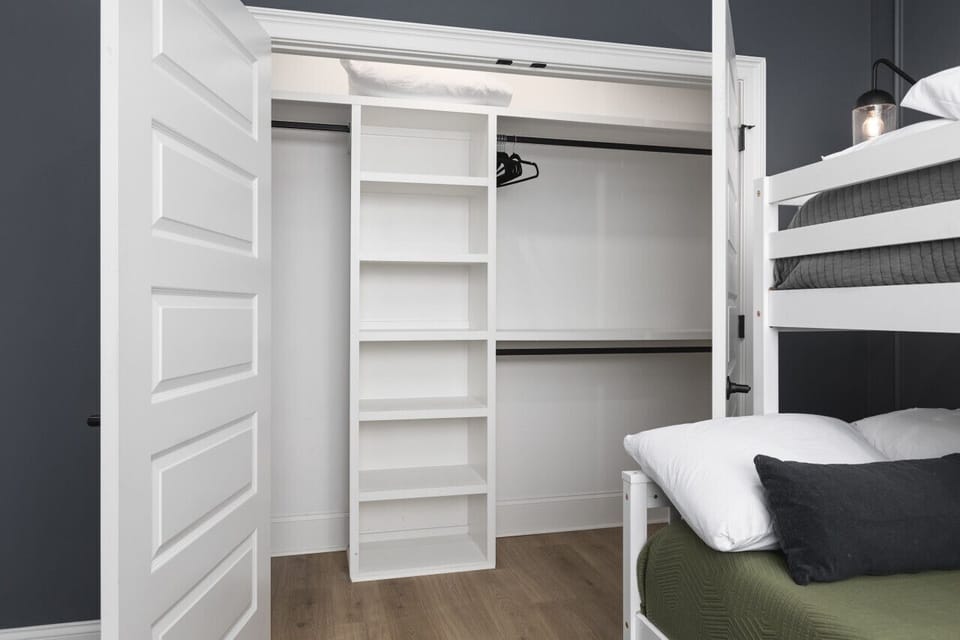Full-over-queen bunk beds in the primary bedroom with a large closet, iron & ironing board, and full-length mirror. This bedroom has an ensuite bath attached as well.