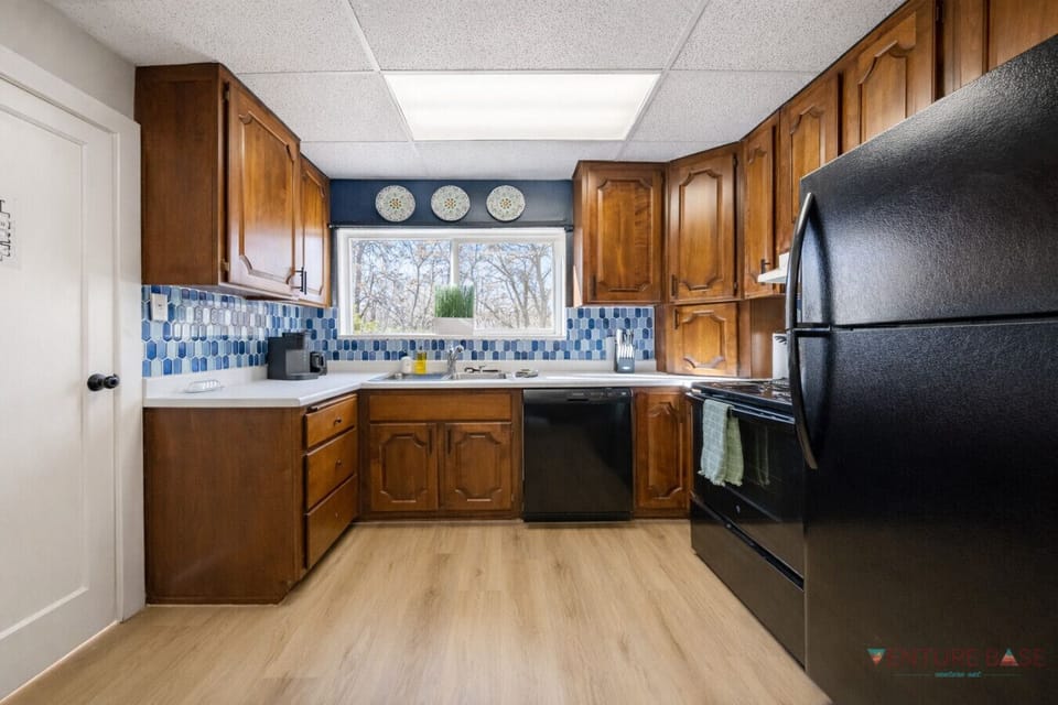 Bright kitchen with wood cabinets, black appliances, and window view.