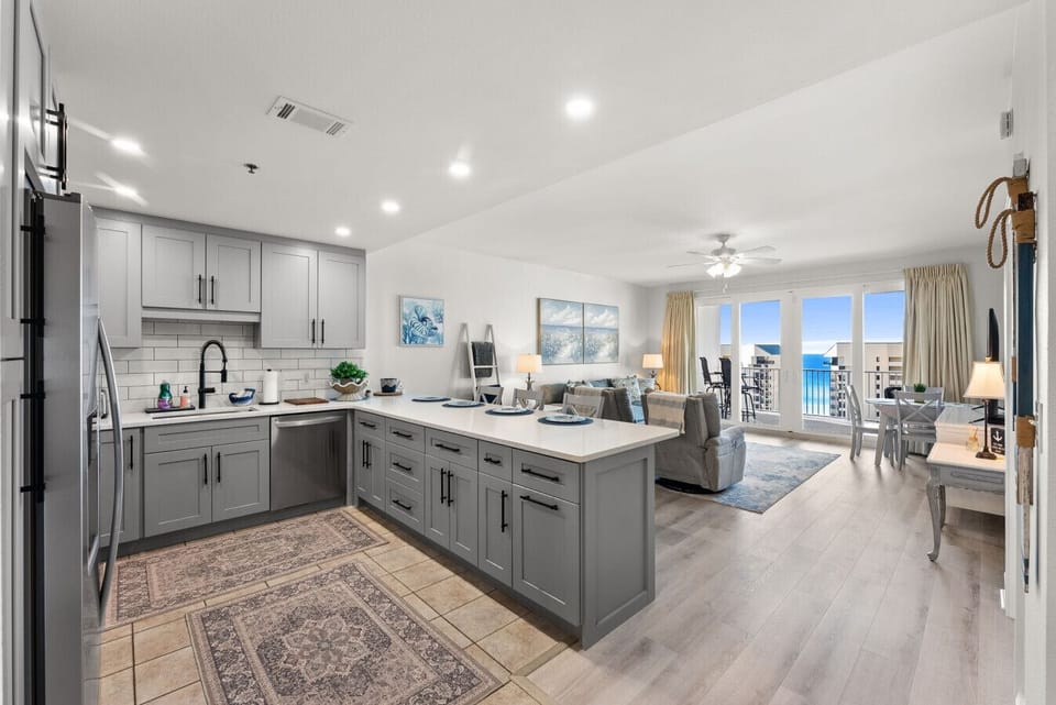 Open-concept layout connects the modern kitchen to the bright living area with stunning Gulf views through floor-to-ceiling windows.