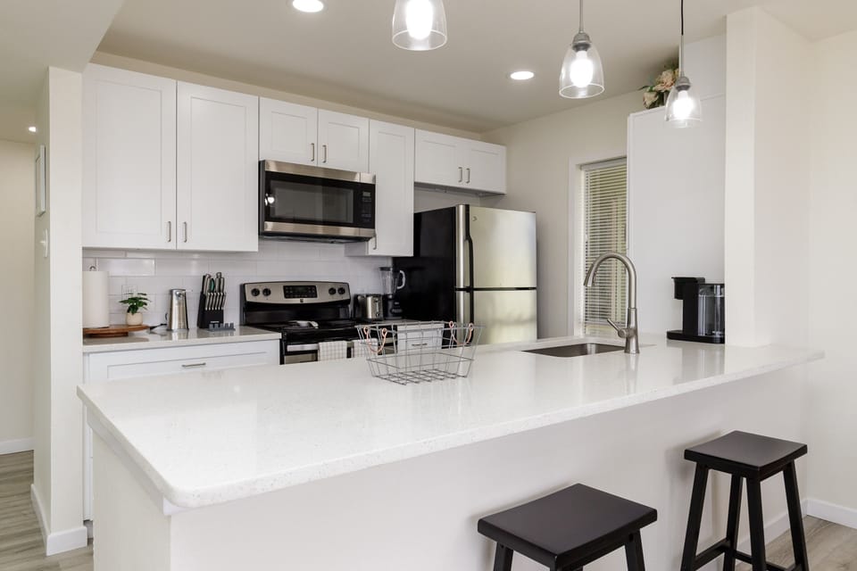 Your modern kitchen features sleek white cabinets, stainless appliances, and a spacious island perfect for cooking and casual dining.