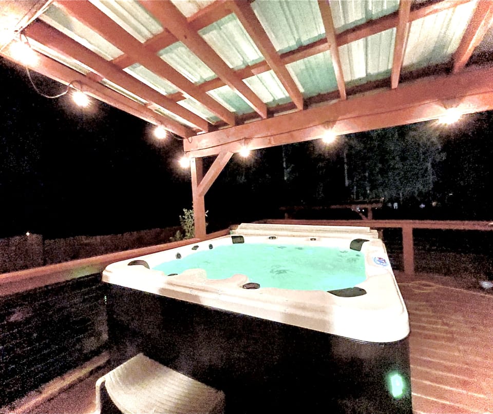 Hot tub and covered deck with plenty of lighting for nighttime use.