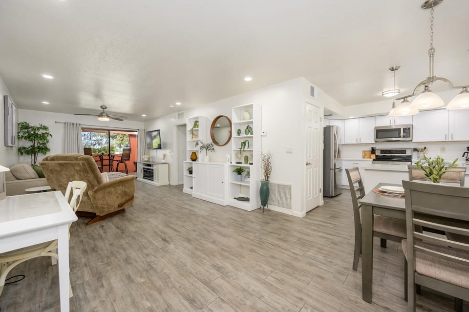 Open-concept living and dining area features wood-look tile floors, white walls, and sliding glass doors to a balcony.