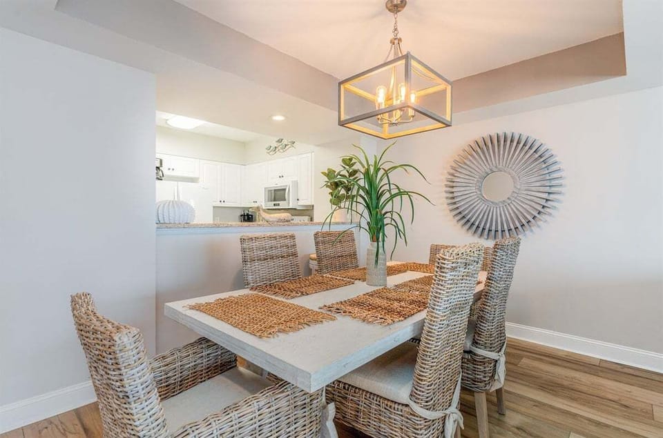 The elegant dining area features a large white table and woven chairs, ideal for family meals or a night of board games.