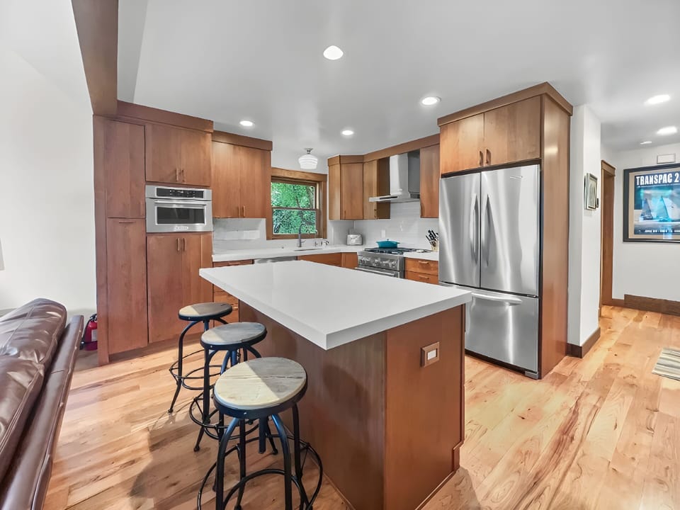 Cook in style in this fully equipped modern kitchen, featuring stainless steel appliances, a breakfast bar island, and warm wood cabinetry.