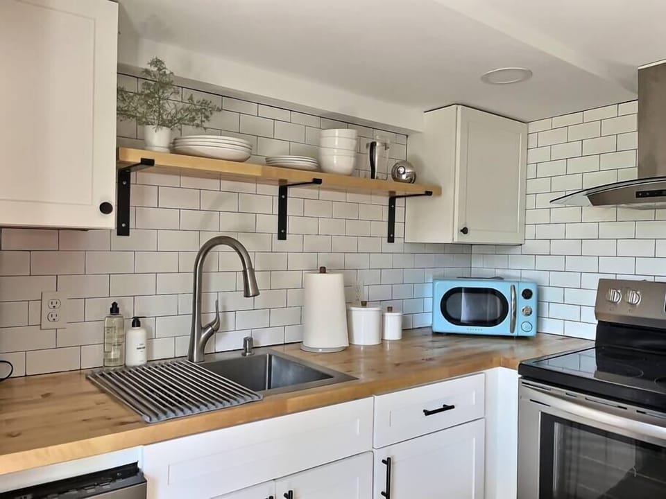 Open shelving and subway tile gives our kitchen clean lines with matte black details for contrast. Fully stocked to cook and dine in.
