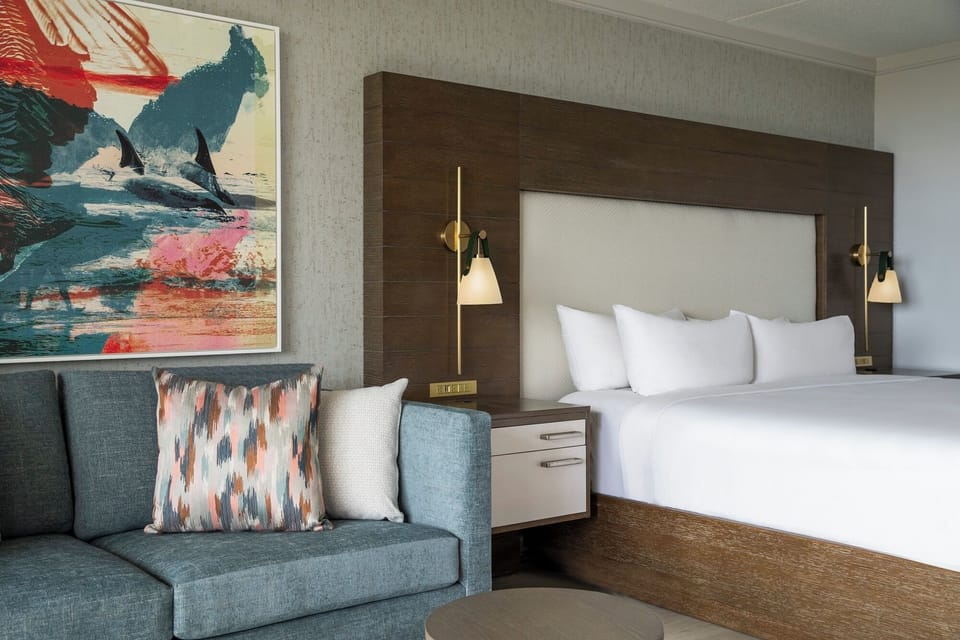 Sink into crisp linens beside a cozy, art-filled sitting area.