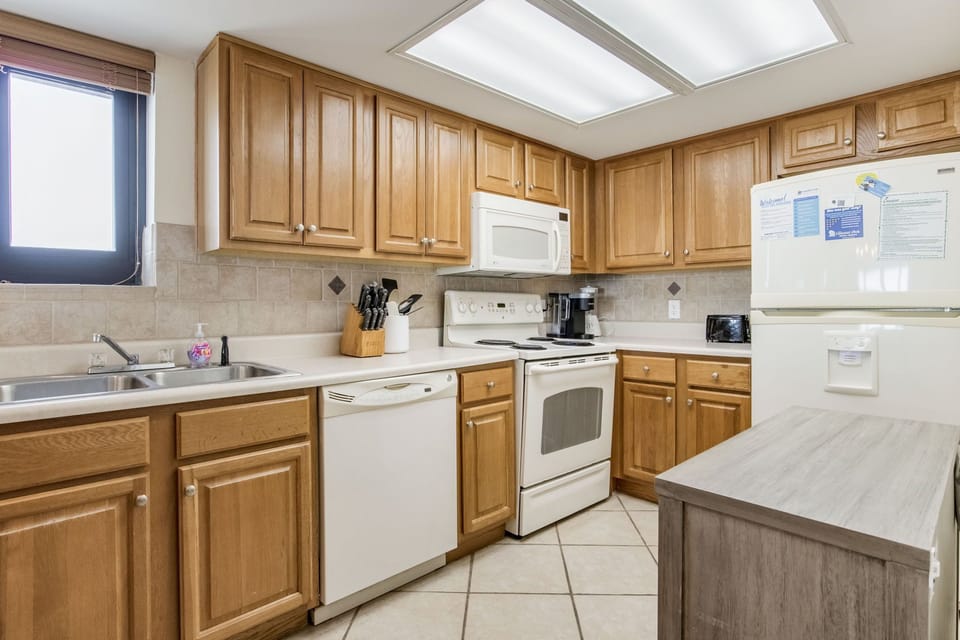 Fully equipped kitchen with oak cabinets and breakfast bar seating at Wind Drift Orange Beach beachfront vacation rental