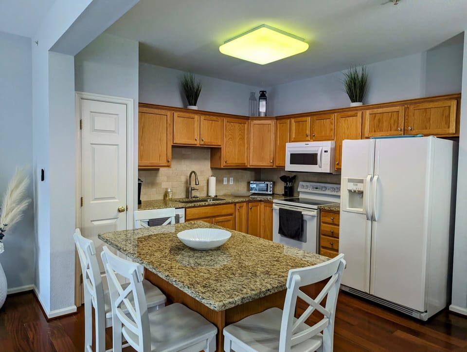 38157 Greenport Lane, South Hampton - chef's kitchen - Functional kitchen featuring warm wood cabinetry, a breakfast bar with seating, and modern white appliances.
