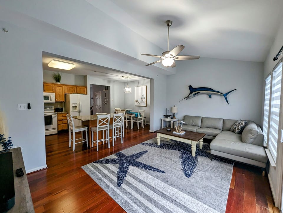 38157 Greenport Lane, South Hampton - open living - Perspective of the expansive main level highlighting the hardwood flooring, granite breakfast bar, and coastal marlin wall decor.