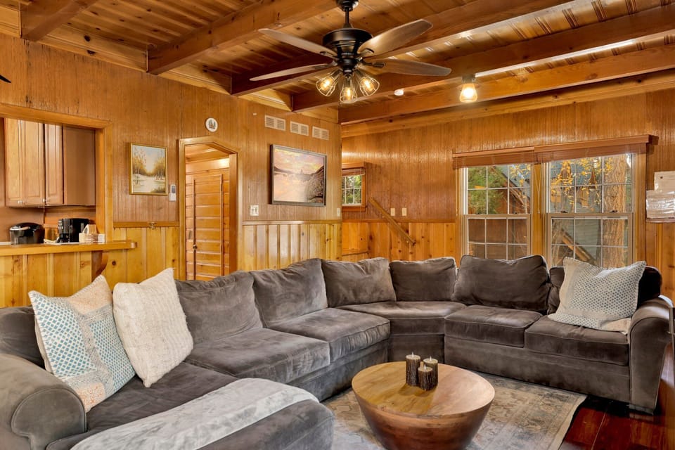 Cozy mountain living room with a stone fireplace, comfy seating, and smart TV—perfect for relaxing evenings, movie nights, and warm cabin vibes after outdoor adventures.