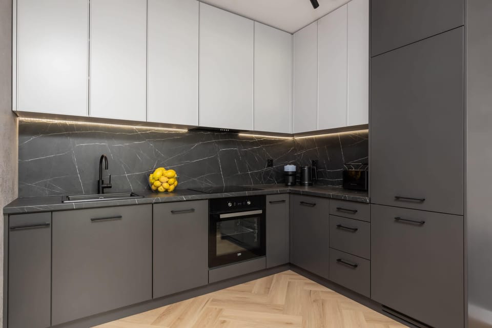 A sleek kitchen with dark cabinets, a built-in oven, and a modern backsplash.