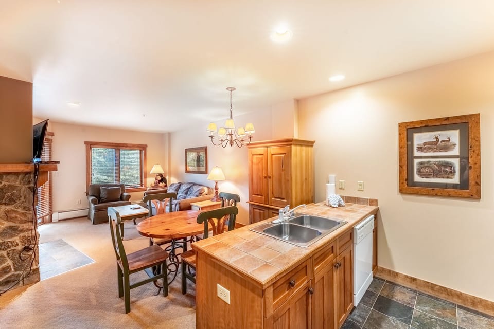 Relax in your cozy living space with warm wood accents, stone fireplace, and fully equipped kitchen for memorable mountain getaways.