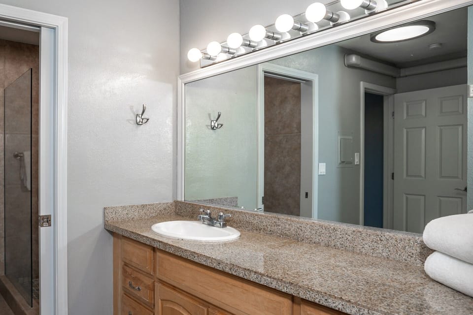Refresh in your private bathroom with bright vanity lighting, a granite countertop, and plush towels waiting for you after a warm shower.